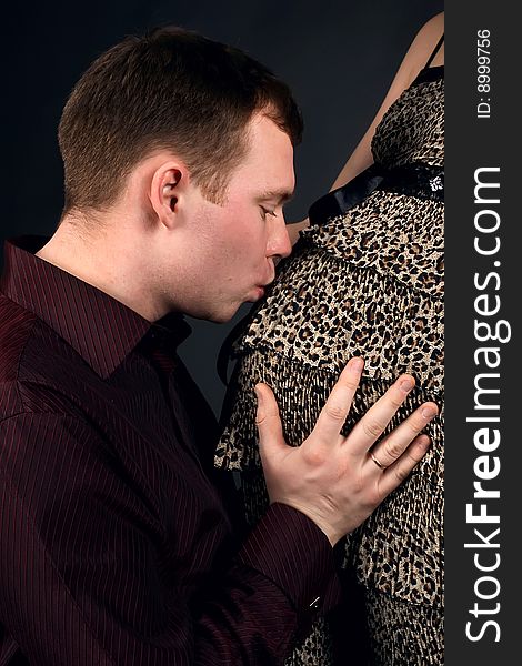 Young beautiful married couple the birth of the second child wait. Dark background. New photos every week