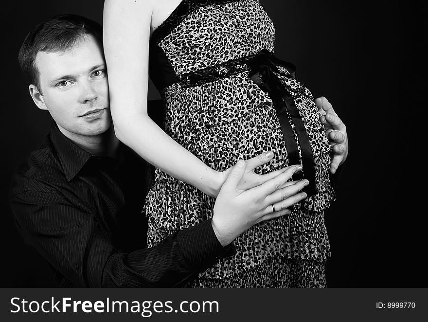 Young beautiful married couple the birth of the second child wait. Dark background. New photos every week