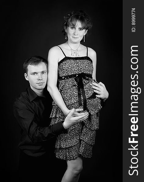 Young beautiful married couple the birth of the second child wait. Dark background. New photos every week