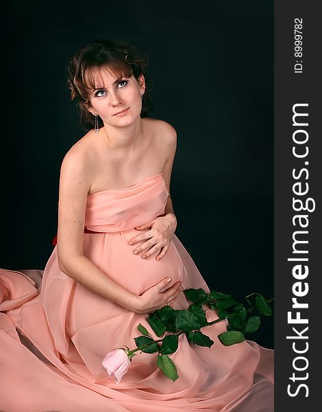 Pregnant woman on dark background. New photos every week