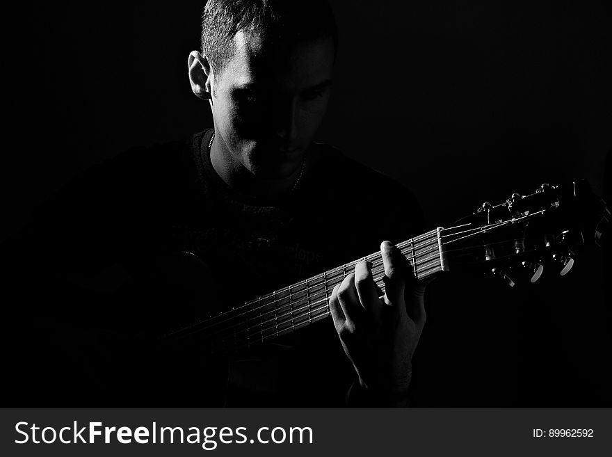 A man playing the guitar in the dark. A man playing the guitar in the dark.