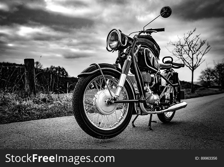 A black and white photo of a motorbike on a road. A black and white photo of a motorbike on a road.