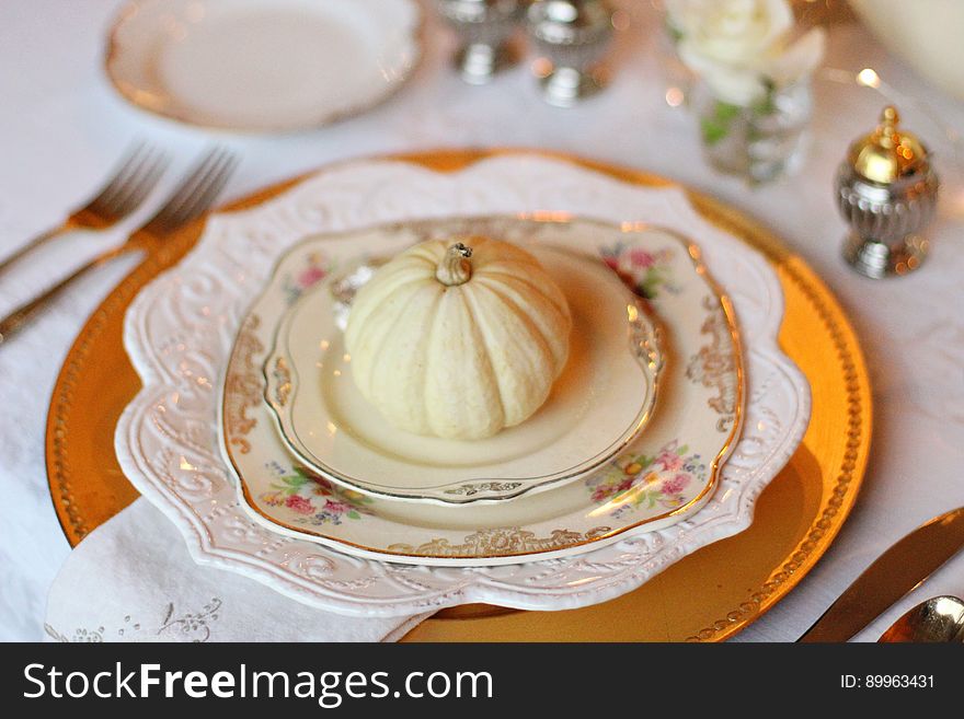 A table set with plates and utensils and a pumpkin on the plate. A table set with plates and utensils and a pumpkin on the plate.