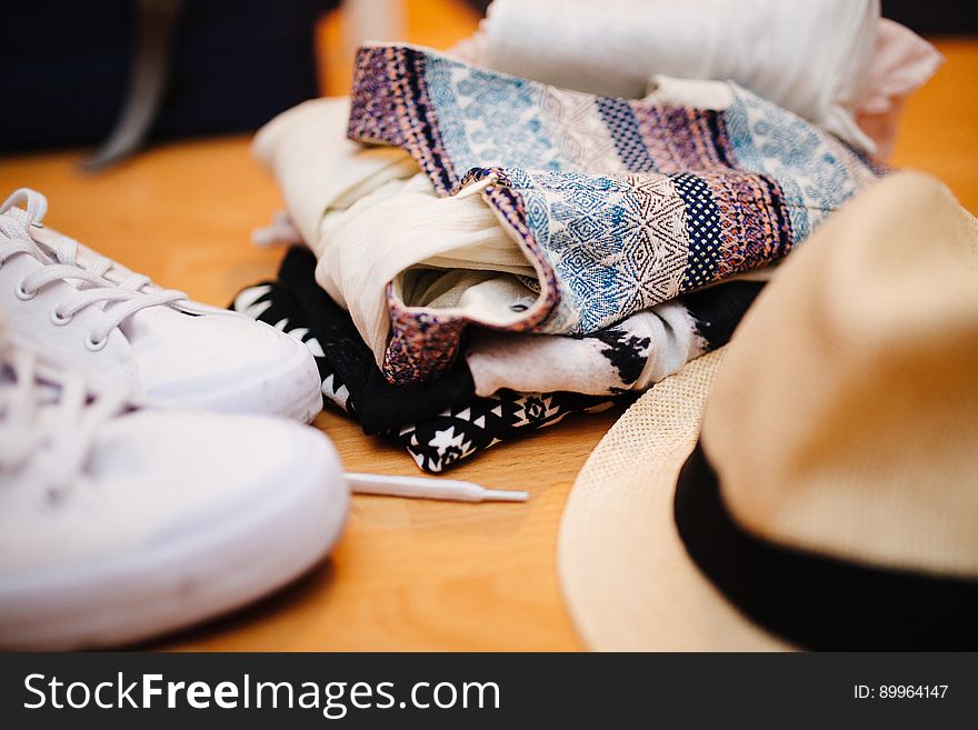 Brown Fedora Hat Beside White Sneakers and Blue Textile