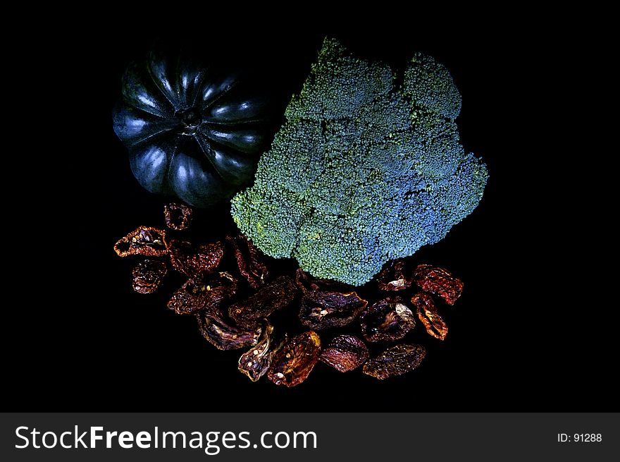 Squash, broccoli and sun-dried tomatos painted with light. Isolated with black background. Squash, broccoli and sun-dried tomatos painted with light. Isolated with black background.