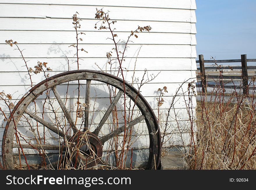 Old antique wagon wheel out front of farm building.