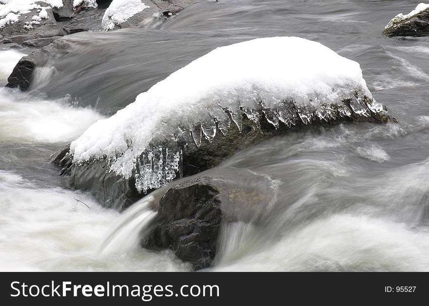 A small snow-covered rock in a river. A small snow-covered rock in a river...