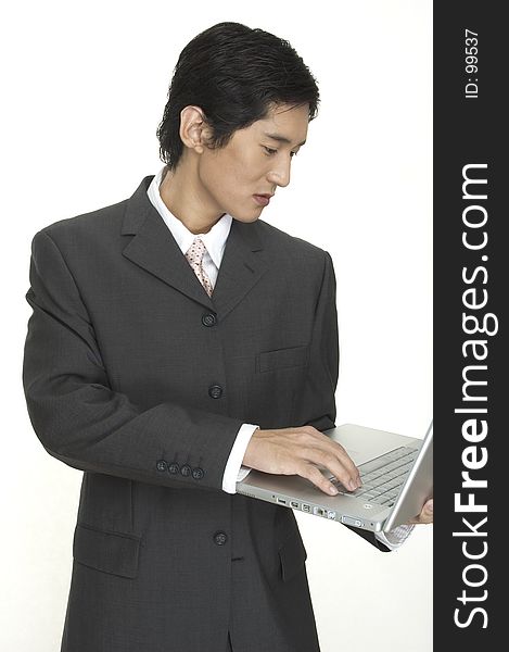 An asian businessman keeps up to date using his laptop computer. An asian businessman keeps up to date using his laptop computer