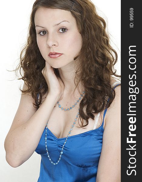 A beautiful young female model in a blue top holds her neck. A beautiful young female model in a blue top holds her neck