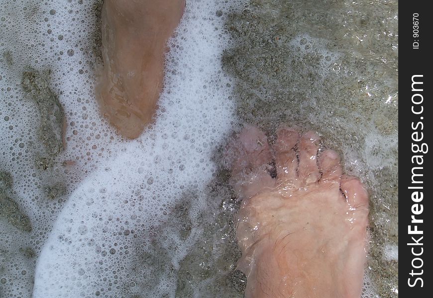 Couples`s feet in water waves