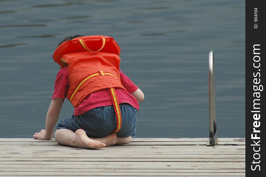 Young boy in life jacket at the end of a dock. Young boy in life jacket at the end of a dock