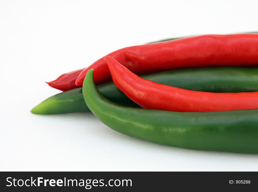 Red banana chilli peppers isolated on white, with green stalk, macro, close up. Red banana chilli peppers isolated on white, with green stalk, macro, close up