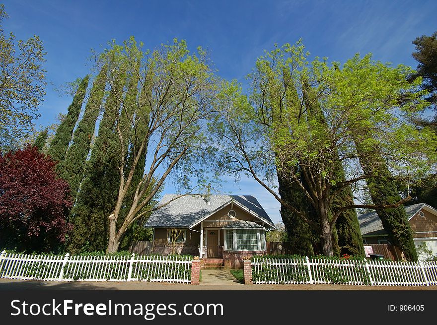 Wide angle view of a house with a white picket fence