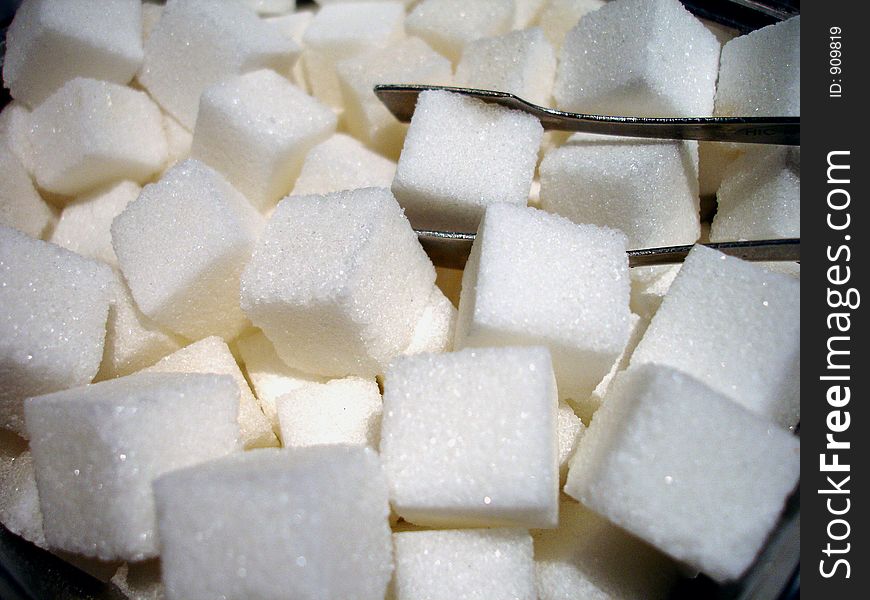 Sugar cubes with pincers in a bowl. Sugar cubes with pincers in a bowl