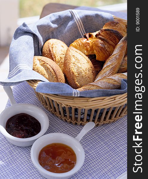 Bread on a wattled tray and two cups with jam