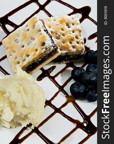 A yummy desert with ice cream, blueberries and chocolate sauce.