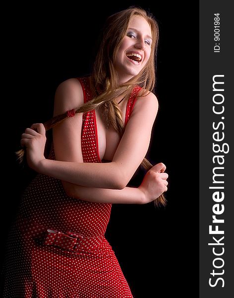 Happy young girl in a red dress holding a hair on a black background
