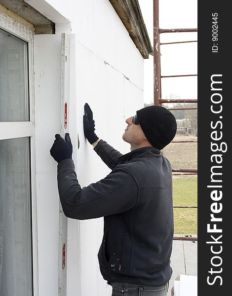 Builder glue polystyrene the plate on wall of the building. check to accuracy of the installation polyfoam plates