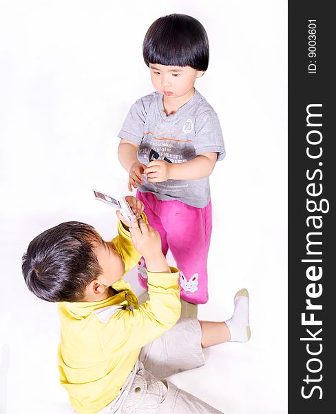 A picture of a little chinese boy taking picture of a little girl with cell phone. A picture of a little chinese boy taking picture of a little girl with cell phone