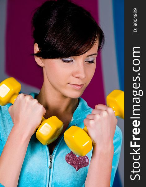 Funny woman curls dumbbells in gym