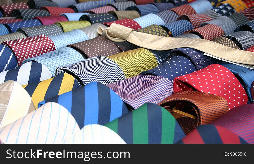 Rolled up colorful ties and one unrolled tie. Rolled up colorful ties and one unrolled tie