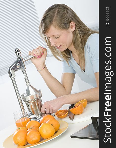 Beautiful girl in the kitchen with juicy orange