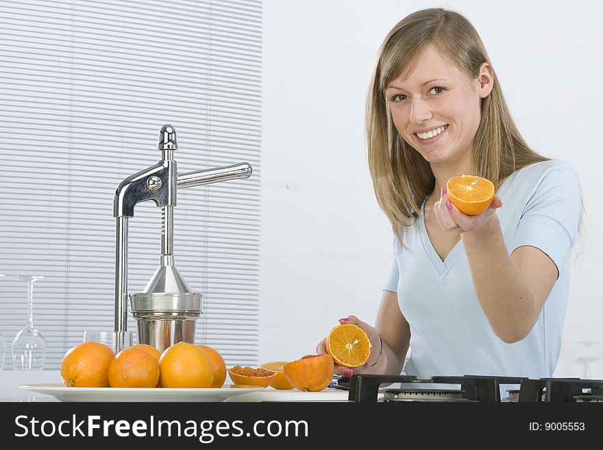 Girl in the kitchen with juicy orange