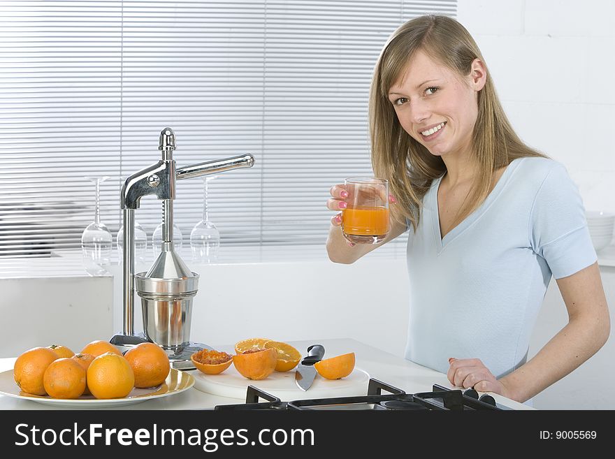 Beautiful girl in the kitchen with juicy orange