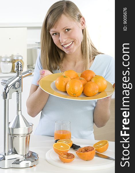 Beautiful girl in the kitchen with juicy orange
