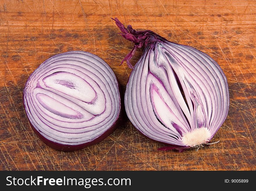 Two slices of violet onion on brown cutting board. Two slices of violet onion on brown cutting board.