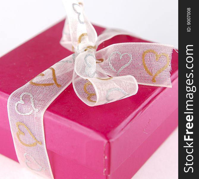 Cute gift box tied with ribbon that has gold and silver heart-shaped patterns on it