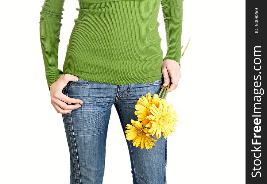 Yellow flowers in a hand of the harmonous girl in jeans