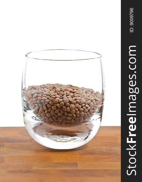 Pardina lentils in glass on wooden table, white background