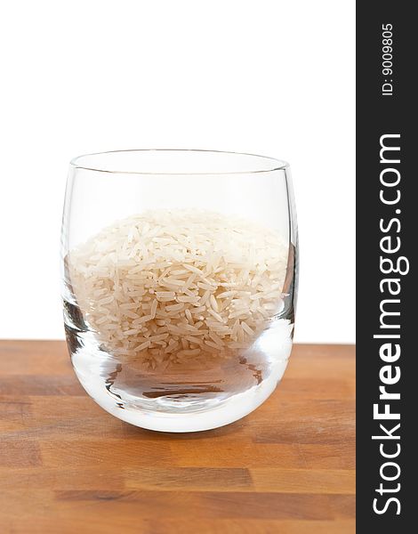 Basmati rice in glass on wooden table, white background