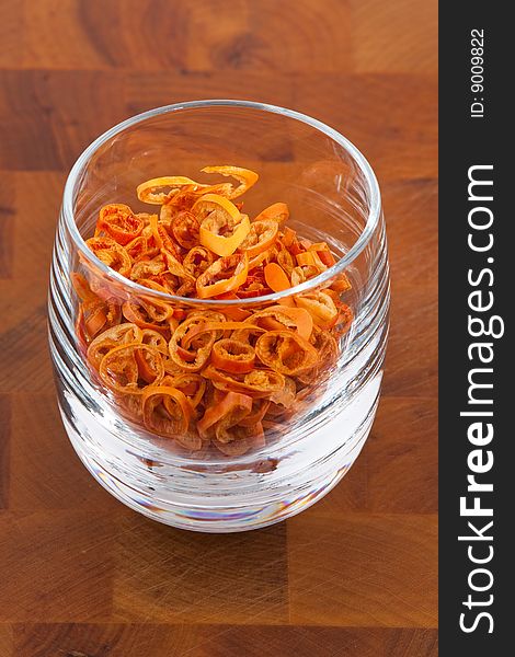 Dried chopped red chilies in glass on wooden table