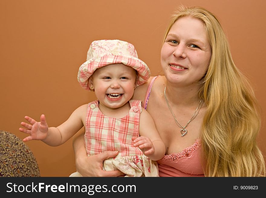 Young beautiful blond blue-eyed mother and daughter smiling portrait. Young beautiful blond blue-eyed mother and daughter smiling portrait