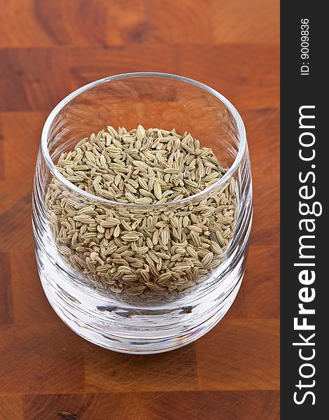 Dried fennel seeds in glass on wooden table