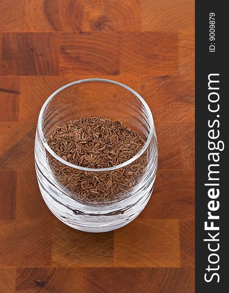 Seeds of dried caraway in glass on wooden table