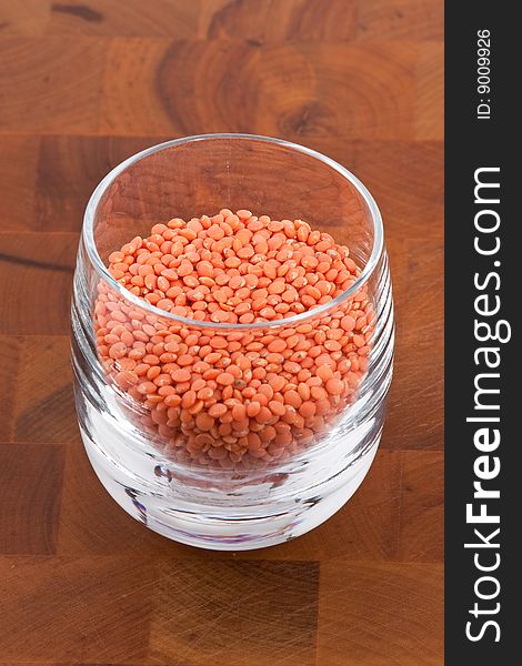 Red lentils in glass on wooden table