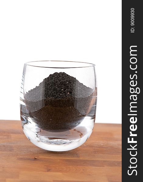 Black onion seeds in glass on wooden table