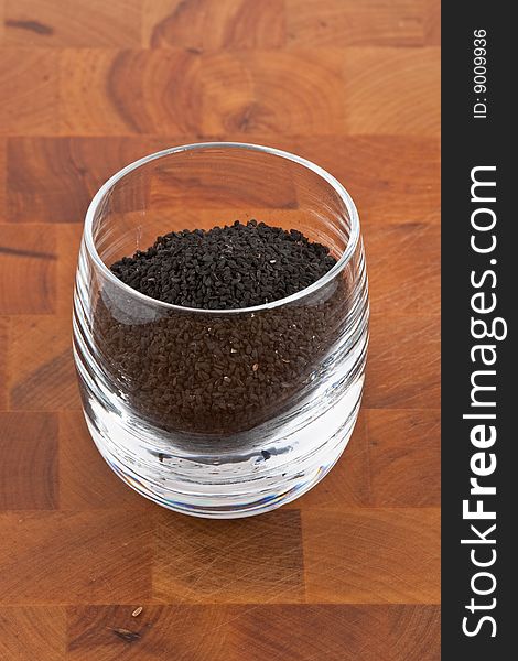 Black onion seeds in glass on wooden table