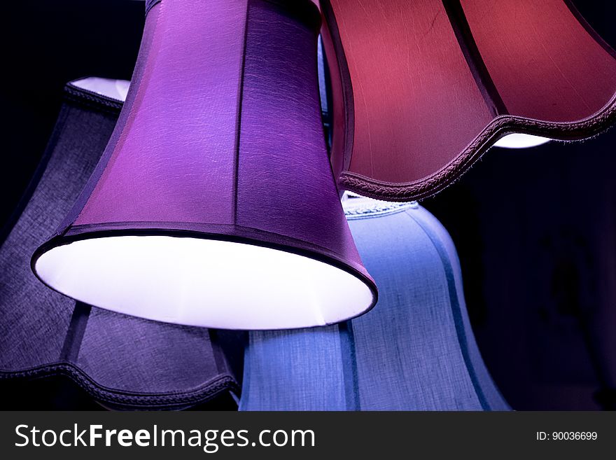 Set of colorful vintage lamp shades hung on dark background.