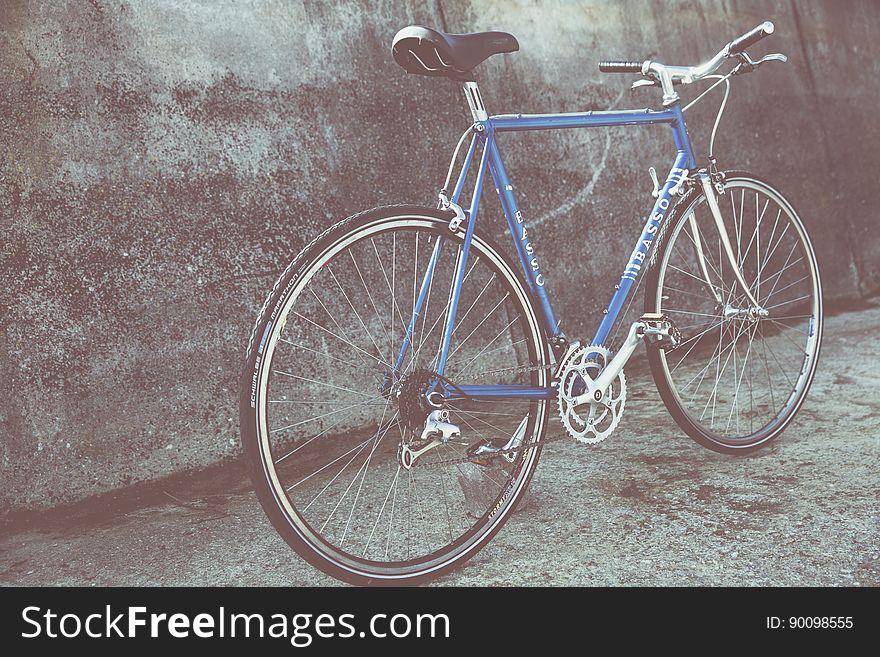 Blue bicycle leaning against cement wall on urban streets. Blue bicycle leaning against cement wall on urban streets.