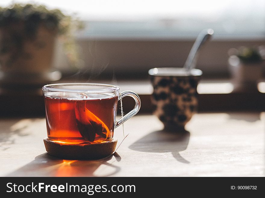 Close up of glass cup of tea on tabletop outdoors on sunny day. Close up of glass cup of tea on tabletop outdoors on sunny day.