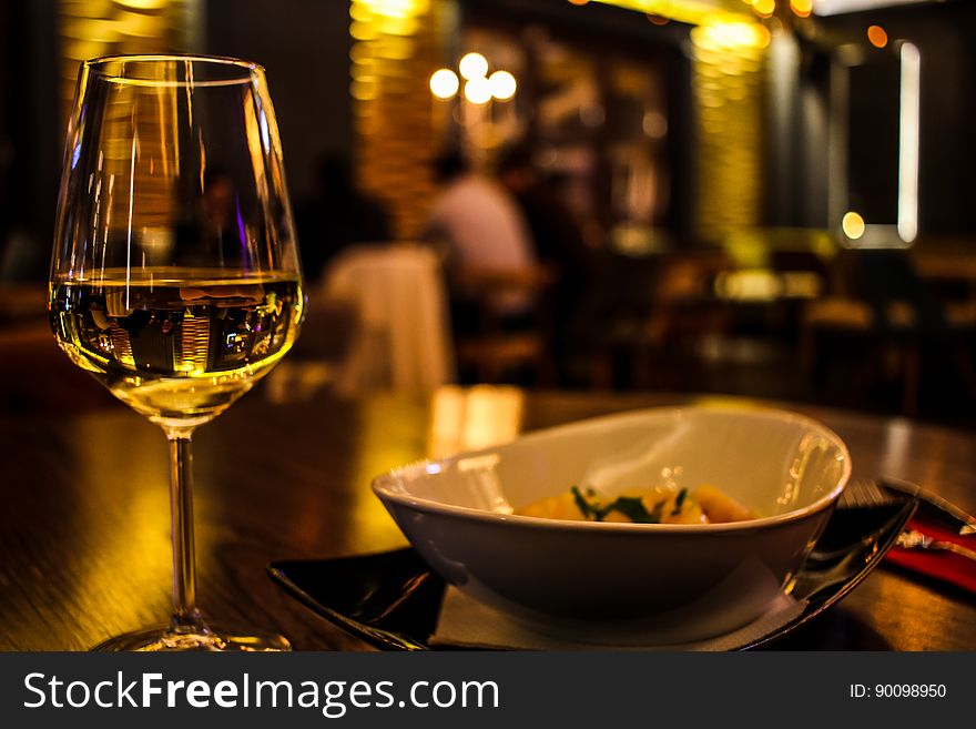 A glass of wine and a plate on the table in a restaurant. A glass of wine and a plate on the table in a restaurant.