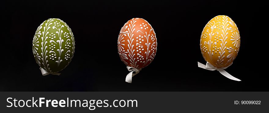 A trio of decorated Easter eggs on black background.