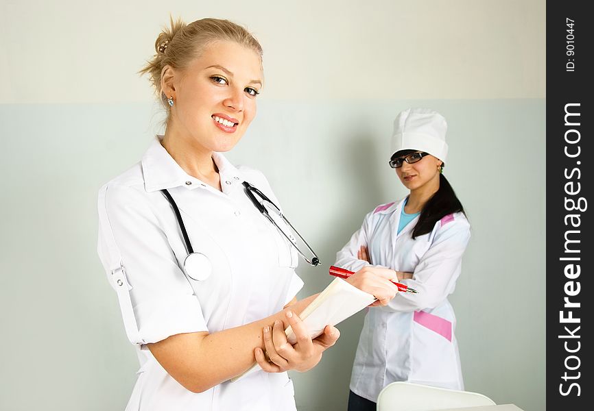 Portrait of a young confident doctor with her assistant in the office. Portrait of a young confident doctor with her assistant in the office