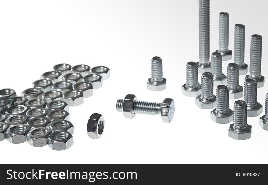 Nuts and bolts on white background separated and ordered. Bolt in center srewed with nut. Nuts and bolts on white background separated and ordered. Bolt in center srewed with nut.