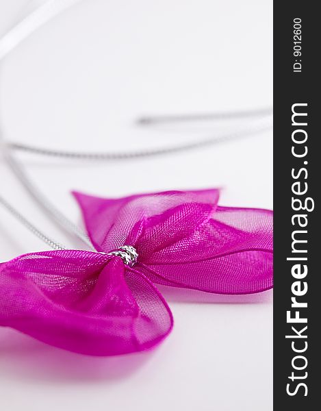 Pink bow tie ribbon with silver cord and white background