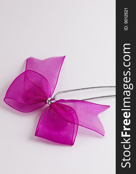 Pink bow tie ribbon with silver cord and white background